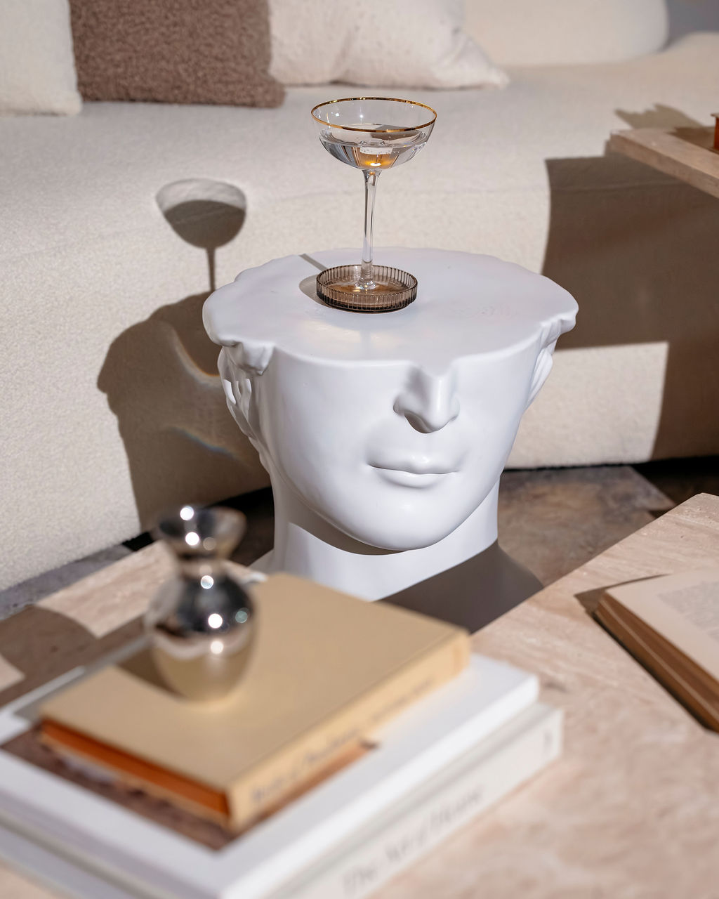Curated sculptural side table with a champagne coupe, styled as part of a Kadeema Rentals editorial furniture vignette.