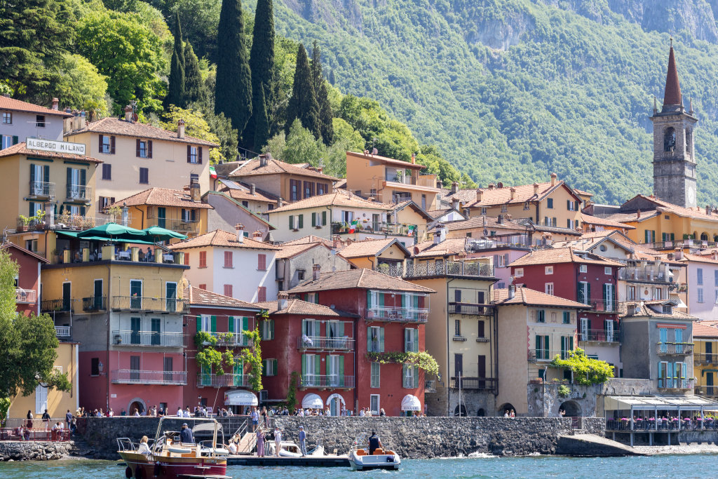 Colorful waterfront village with bell tower and boats on Lake Como, Italy
