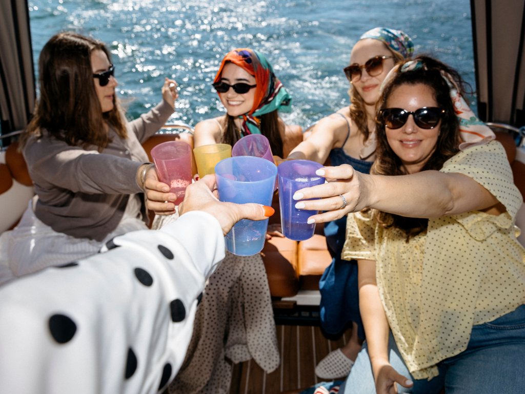 Four women toasting drinks during a boat ride on Lake Como, Italy
